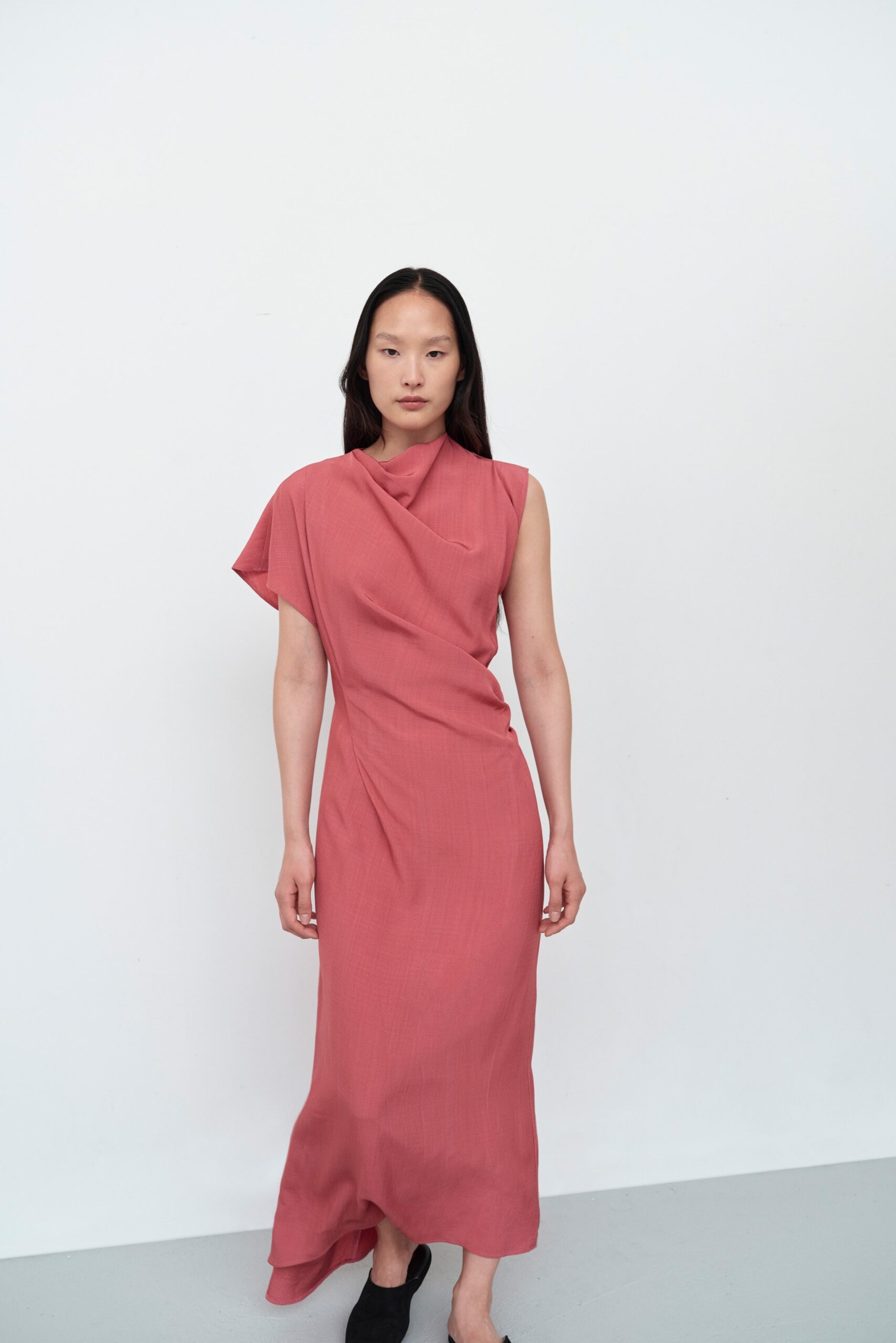 A fitted pink cotton dress with a sleeveless design and asymmetric detailing.