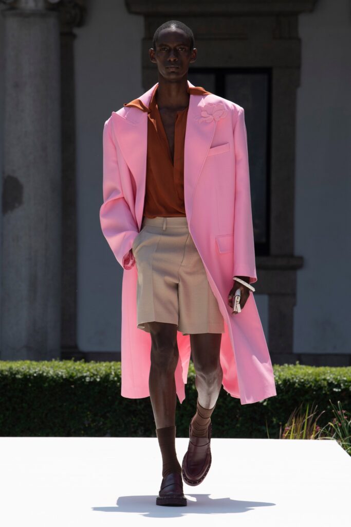 A relaxed pink coat paired with a brown collared shirt, featuring button details.