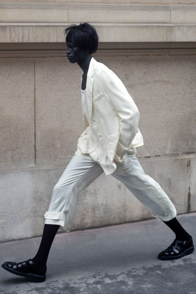 A tailored white suit with long sleeves and a collared design, featuring buttoned details.