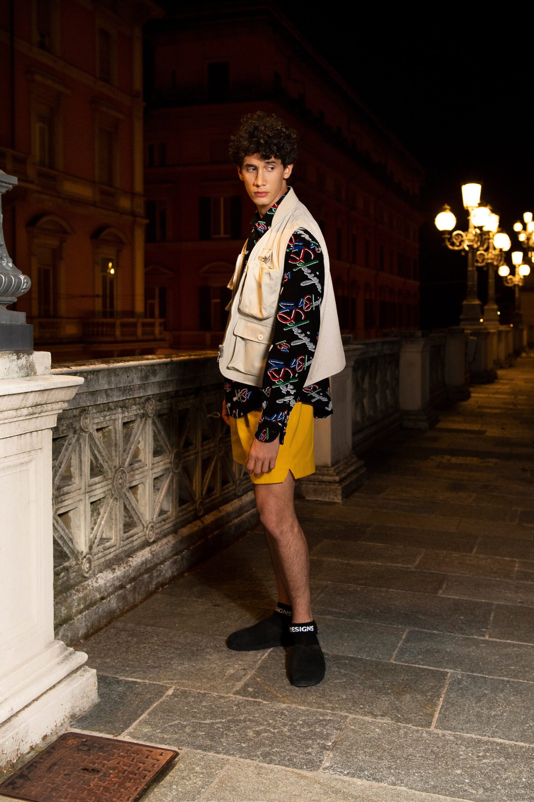 A relaxed fit yellow shorts paired with a black printed short-sleeve collared shirt.