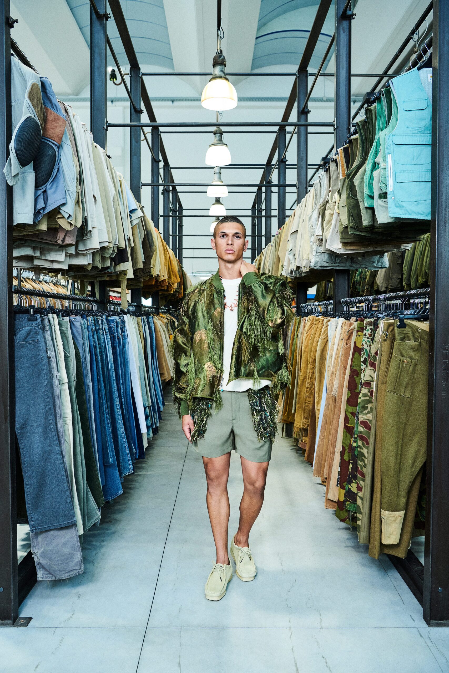 A relaxed green fringed jacket paired with beige shorts, perfect for a casual summer look.
