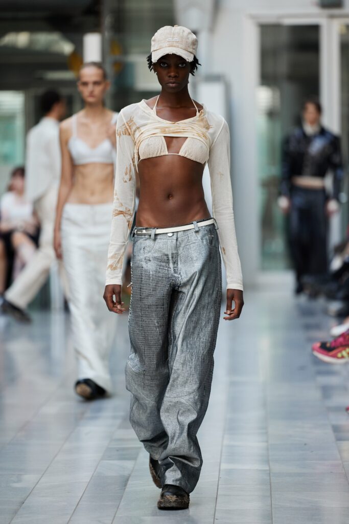 A sleeveless white cotton top paired with high-waisted gray denim pants for a modern look.