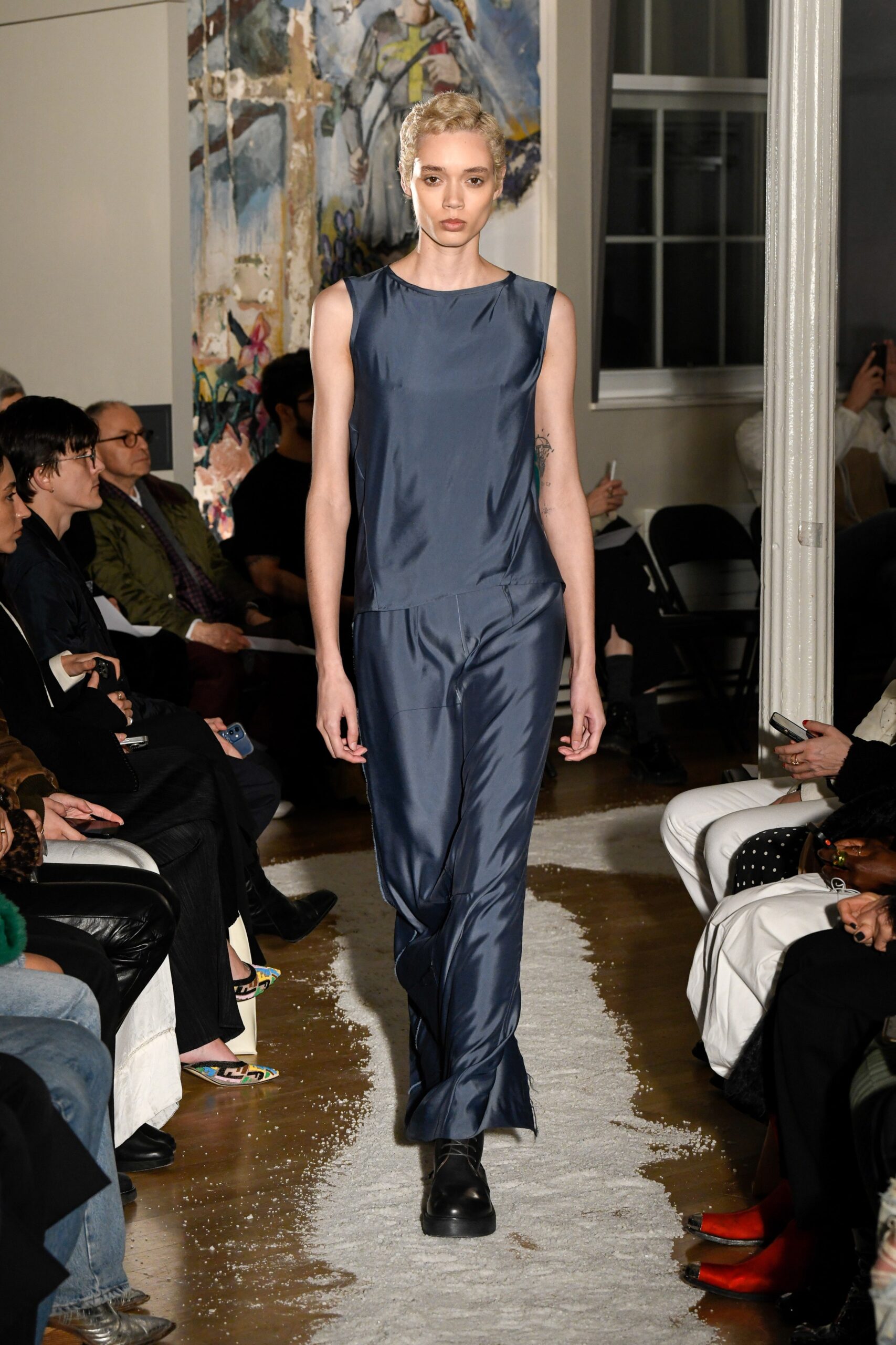 A fitted blue silk sleeveless jumpsuit with a V-neckline and straight-leg design.