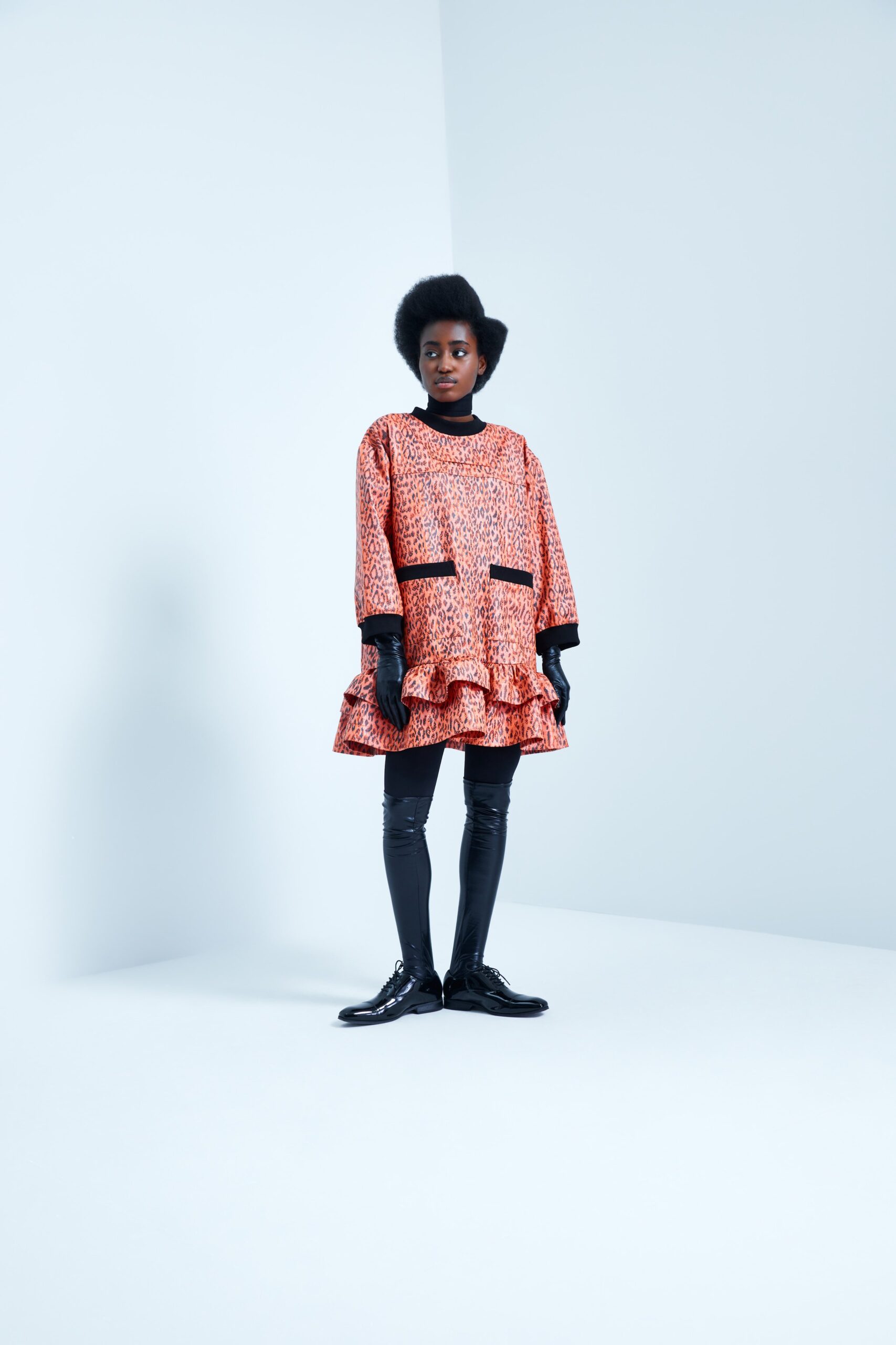 This relaxed dress features a playful ruffled hem and long sleeves, adorned with a vibrant print that adds a dynamic flair. The collared neckline enhances the silhouette, creating a striking contrast with the flowing fabric.