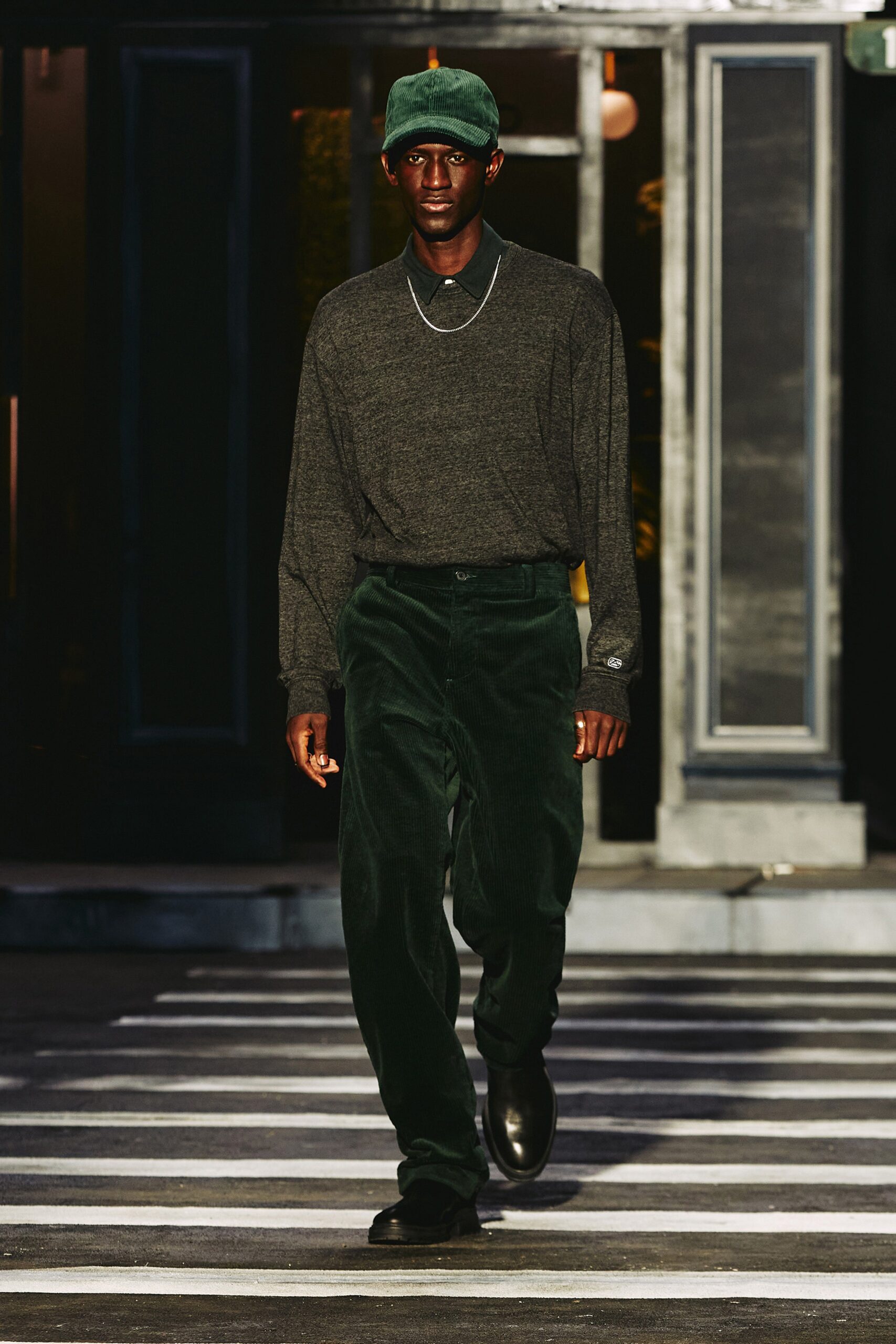 A relaxed gray cotton long-sleeve shirt paired with green velvet straight-leg pants.