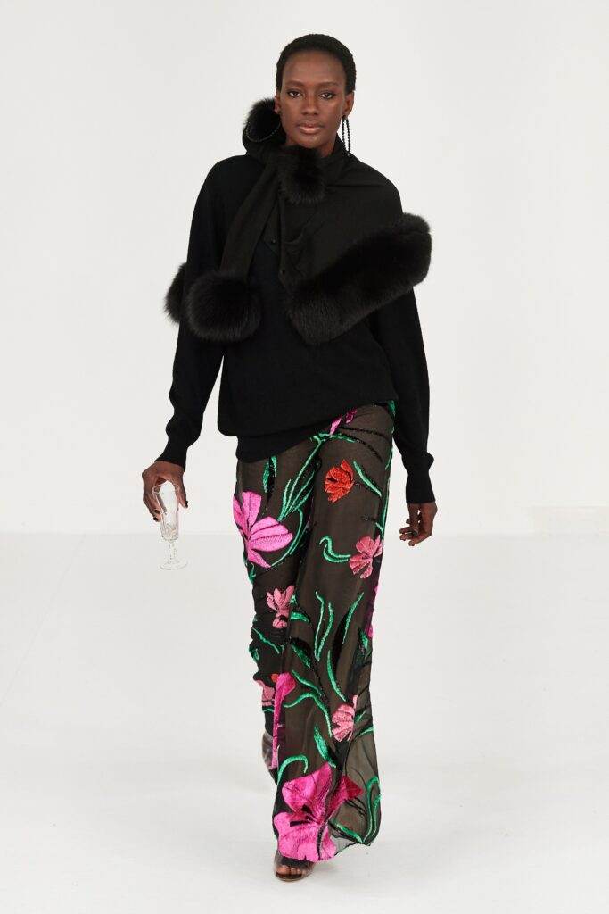 A fitted black silk top with long sleeves paired with a flared, multicolor printed skirt.