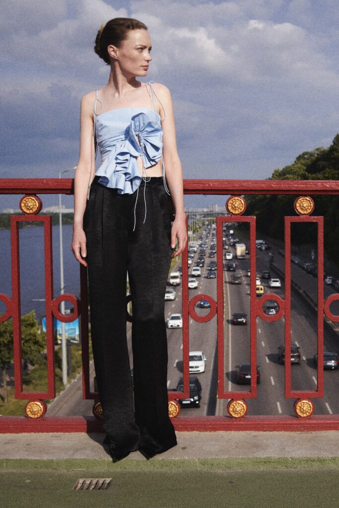 A fitted blue sleeveless top with ruffles paired with black wide-leg pants.