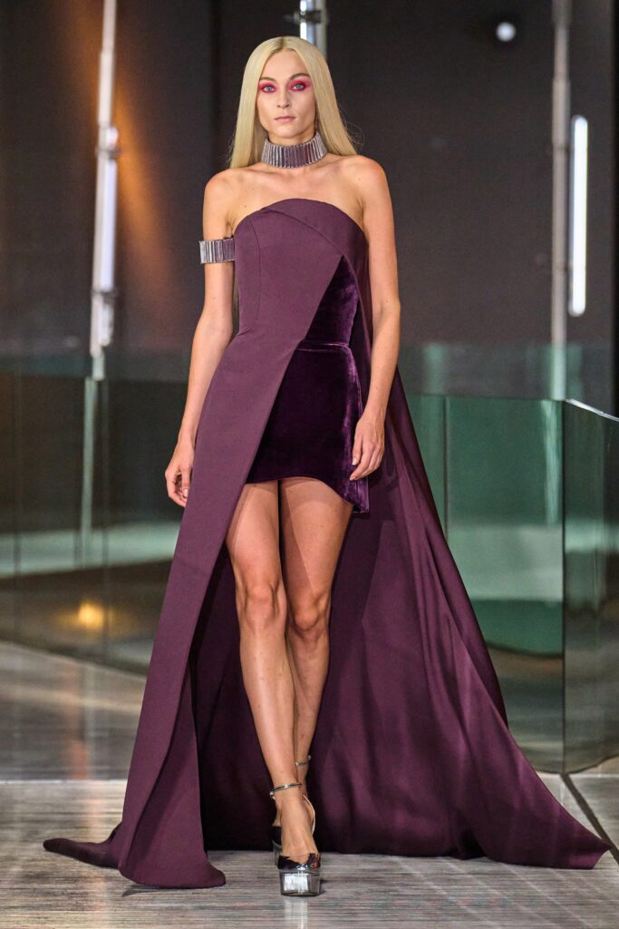 A fitted purple velvet dress with an asymmetric design and a high slit.