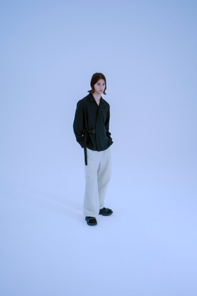 A relaxed black long-sleeve collared jacket paired with wide-leg white pants.