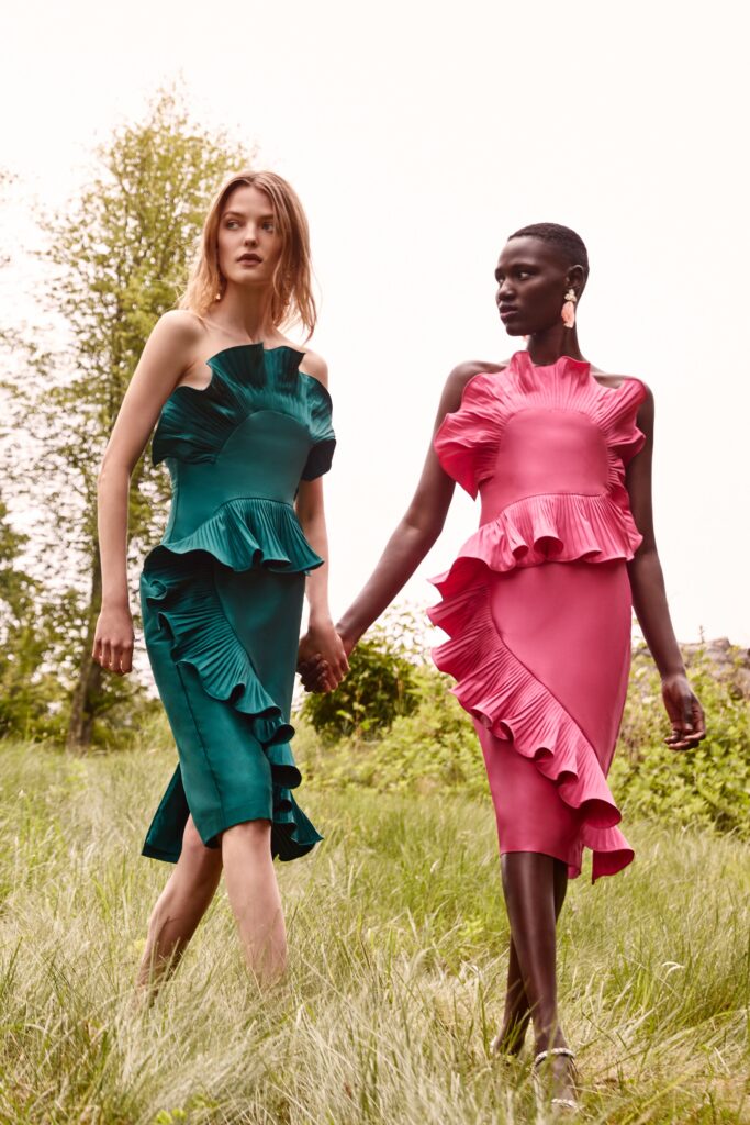 A fitted silk dress with ruffled details and an asymmetric silhouette in green and pink.