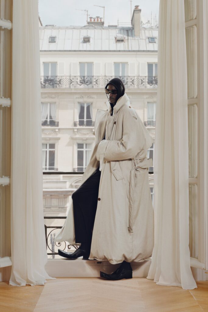 An oversized beige wool coat with long sleeves and a draped design.