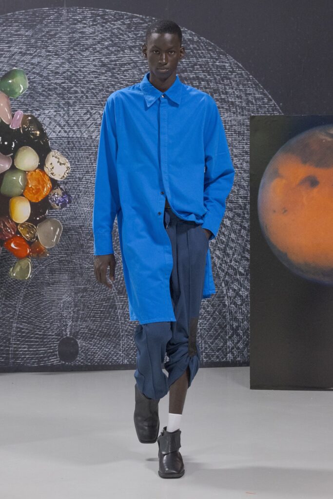 A relaxed blue long-sleeve shirt with a collared neckline paired with black pants featuring an asymmetric design.
