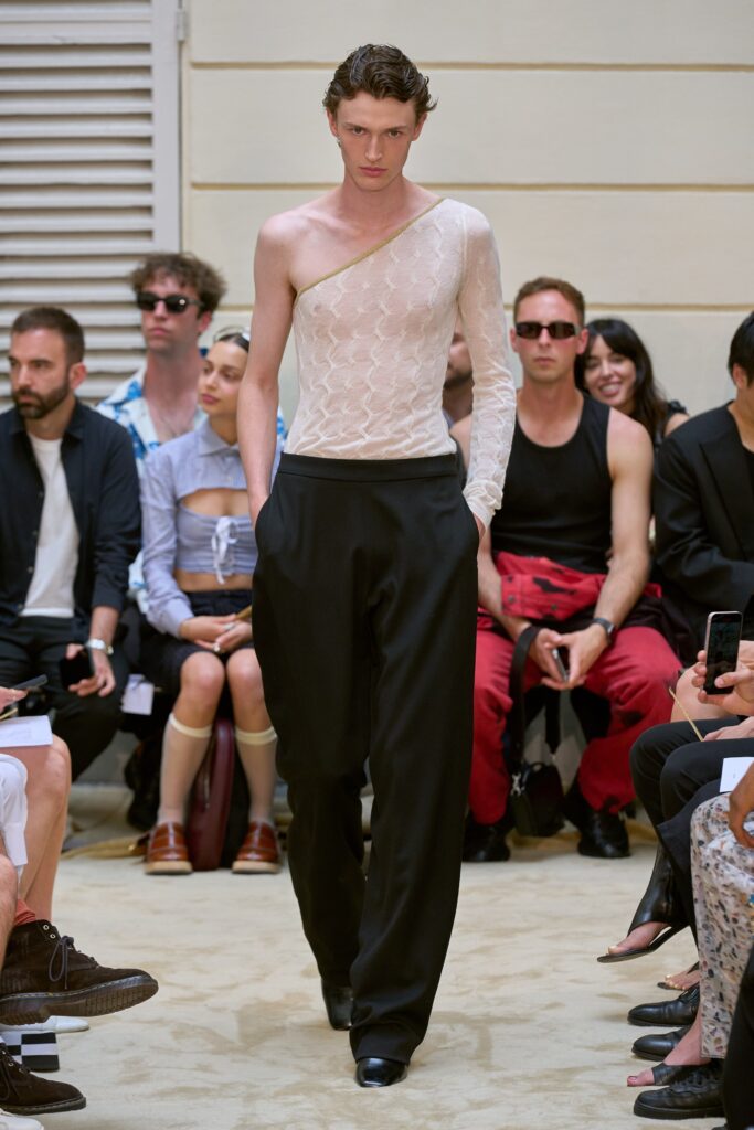 A fitted white asymmetric top with a V-neckline paired with black fitted pants.