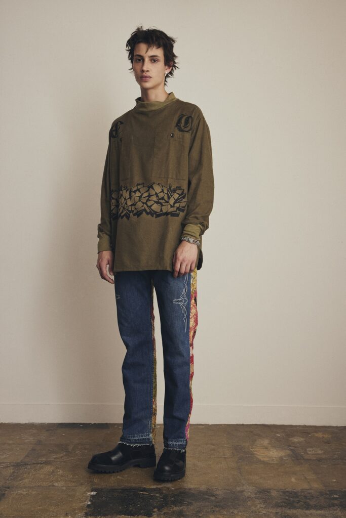 A relaxed long-sleeve green shirt with embroidery paired with straight-leg blue denim pants.