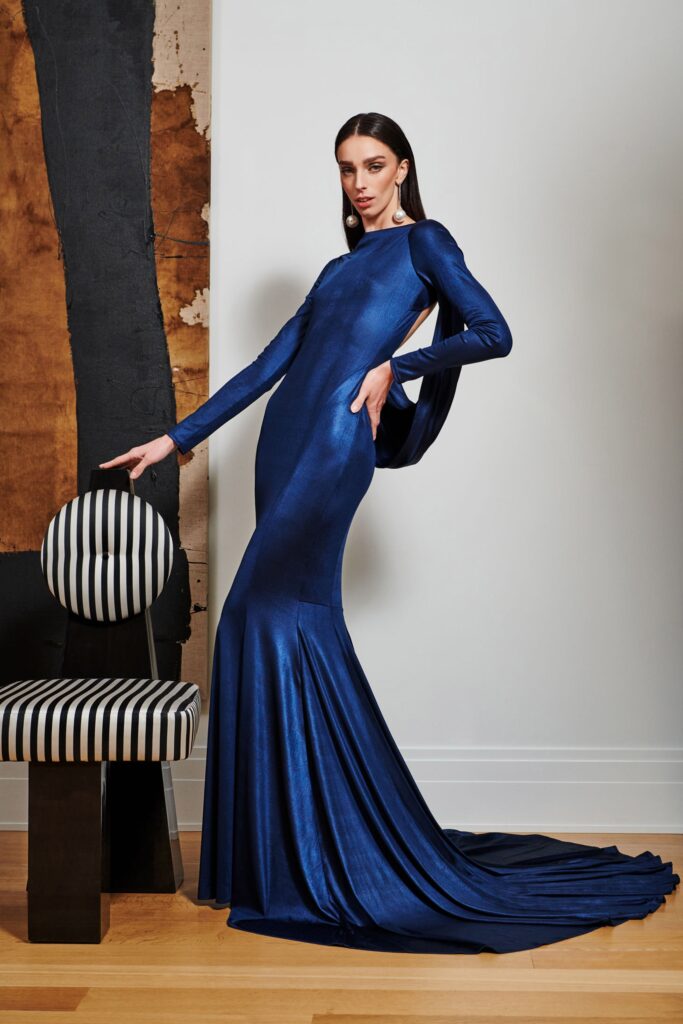 A fitted blue silk gown with long sleeves, a V-neckline, and a flared silhouette.