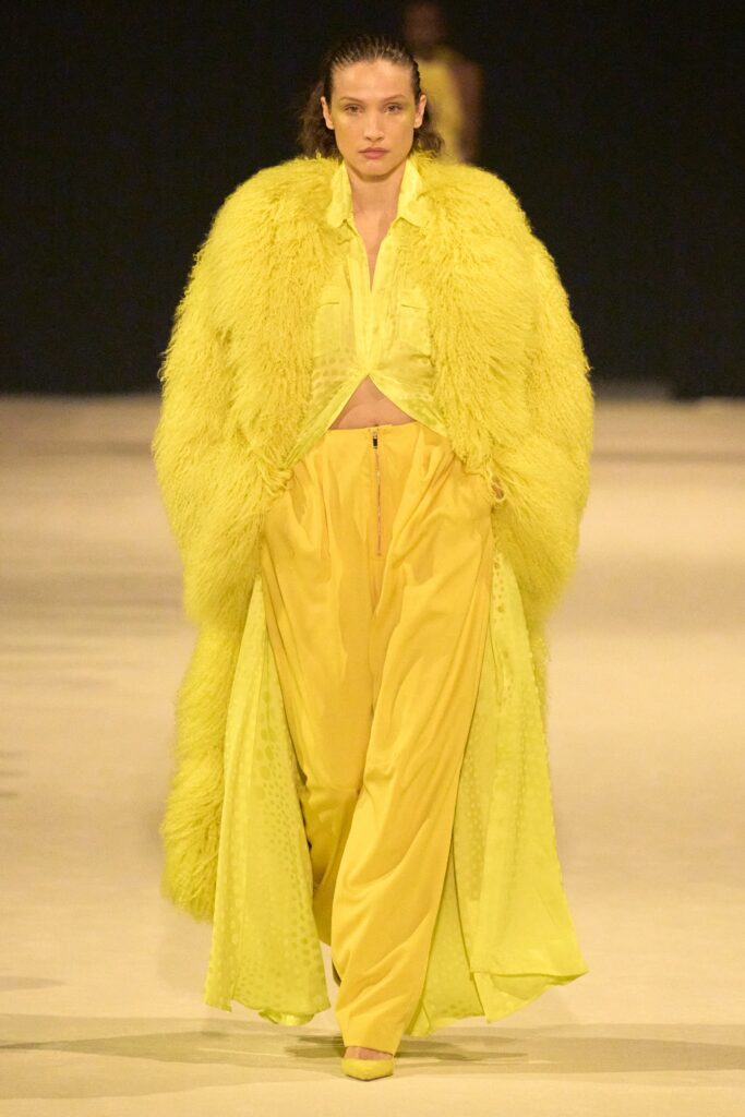 A relaxed yellow fur coat paired with silk pants, featuring a layered design.