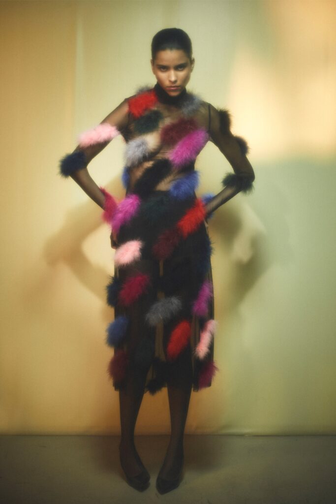 A fitted sleeveless dress made of fur with an asymmetric design and vibrant colors.