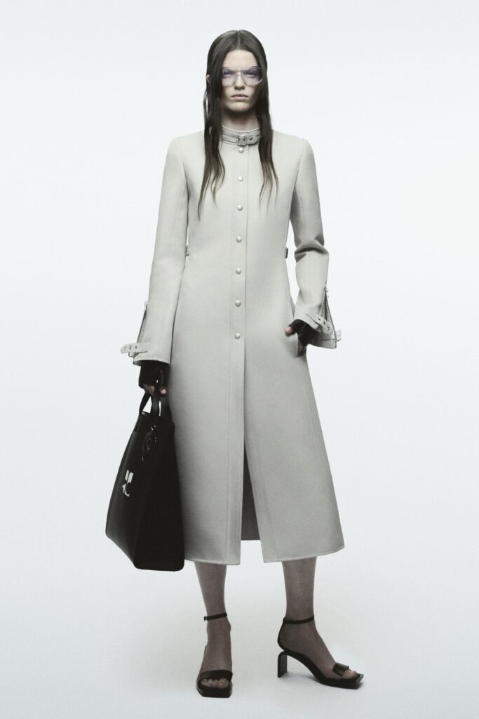 A relaxed beige wool coat with long sleeves and a collared design featuring button details.