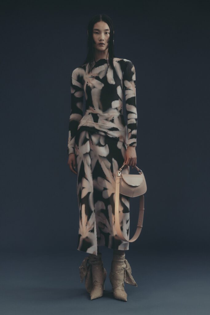 A fitted black and white printed dress with long sleeves and a high neckline.