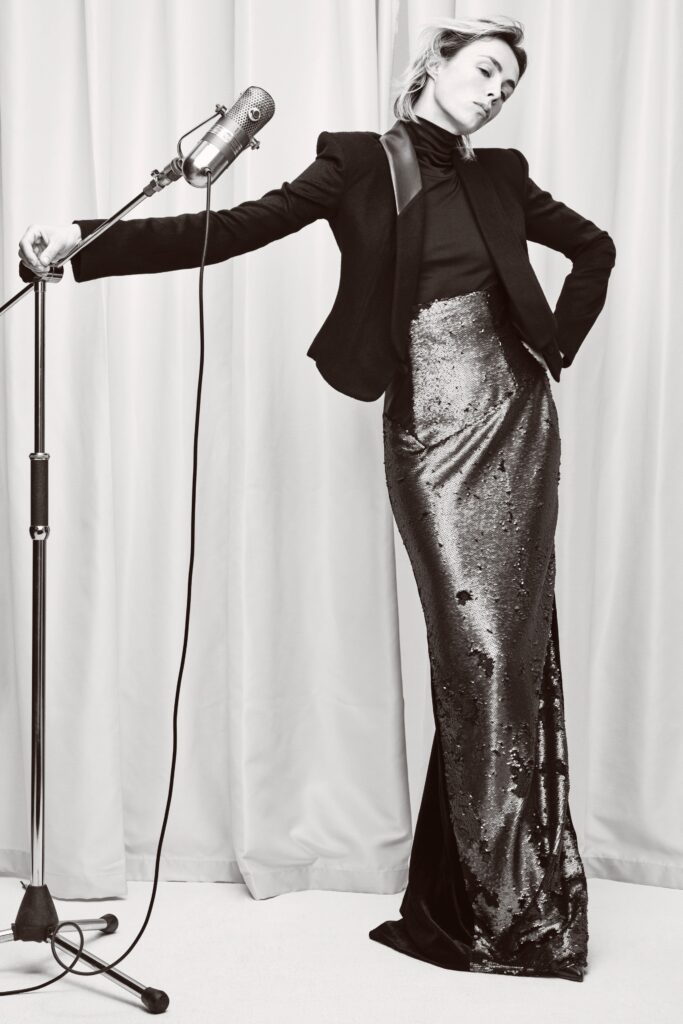 A fitted black sequin dress with a high-neck and pencil silhouette, paired with a blazer.