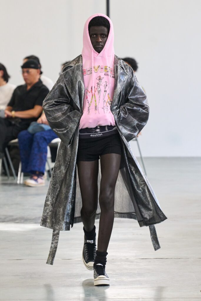A relaxed gray satin coat layered over a pink hoodie with long sleeves and a hood.