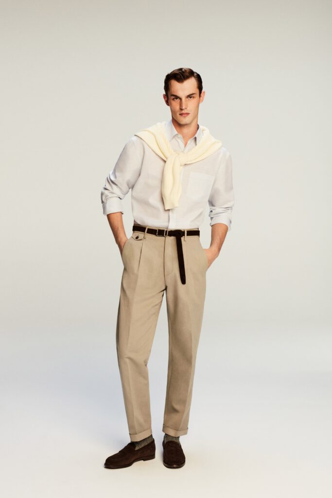 A fitted white long-sleeve shirt with a collar paired with pleated beige pants.