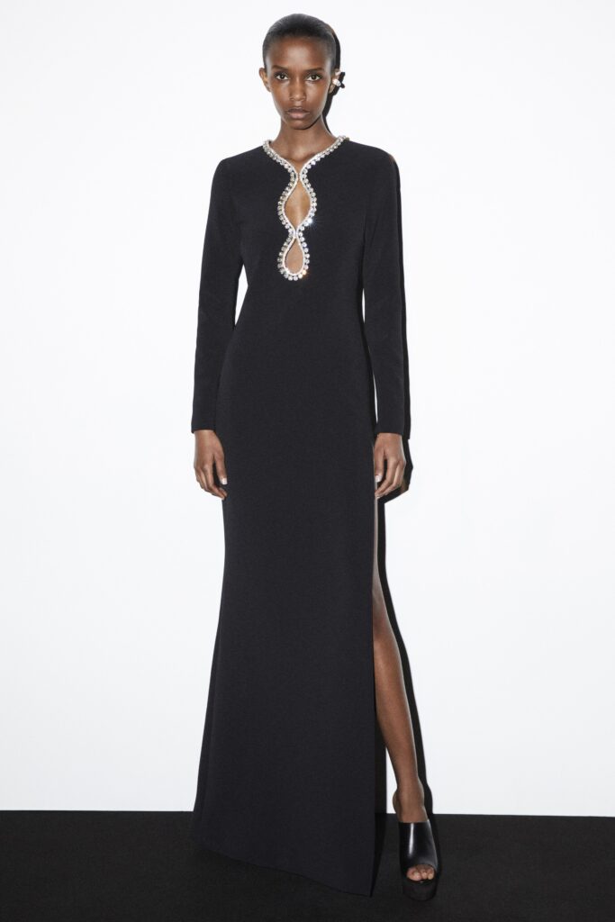 A fitted black silk gown with long sleeves, a V-neckline, and a stylish slit.
