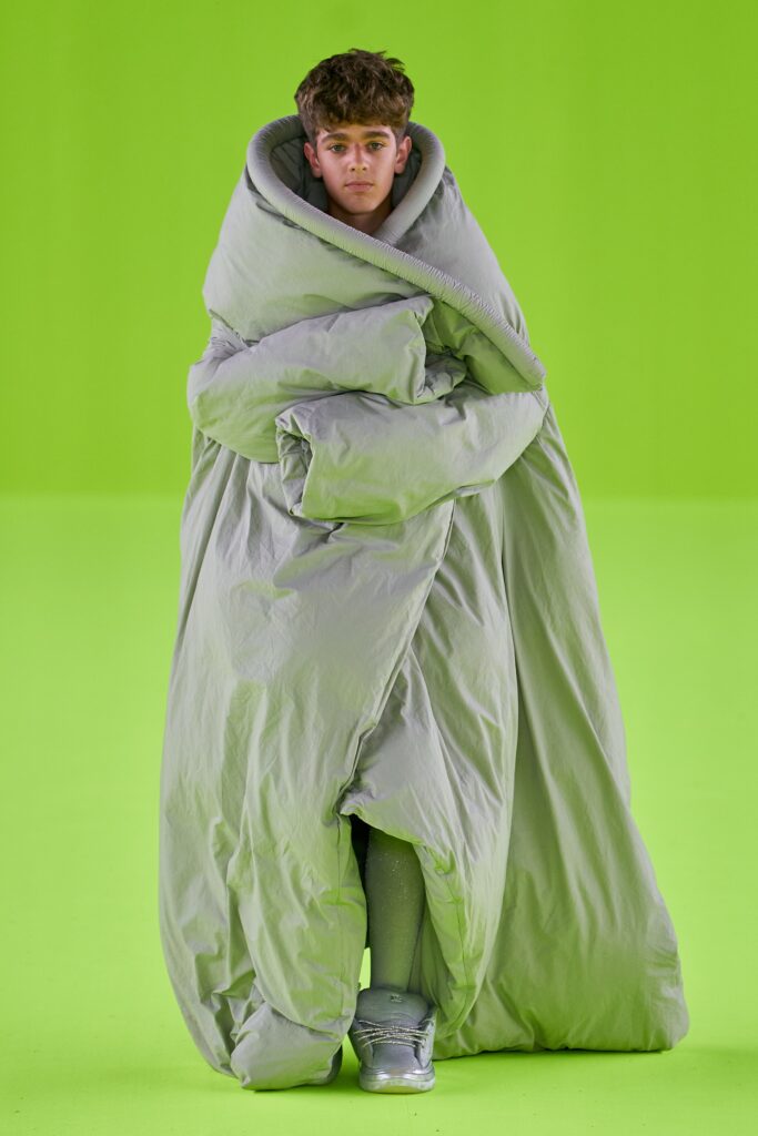 An oversized green coat made of cotton with long sleeves and a layered design.