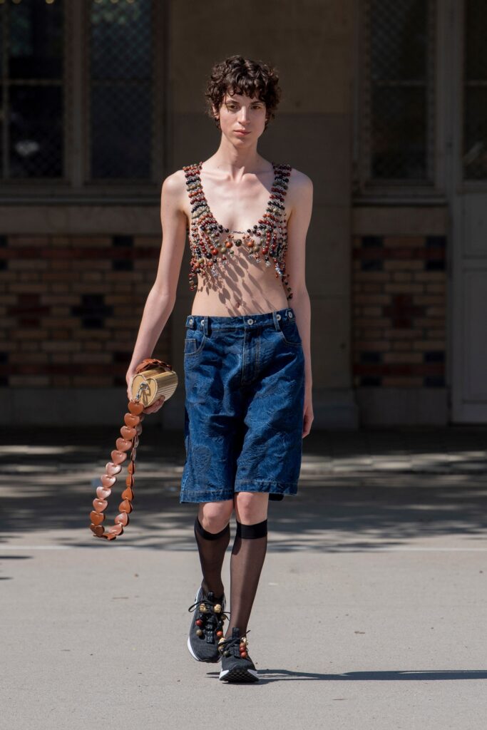 A fitted blue denim sleeveless top with embroidered details paired with denim shorts.