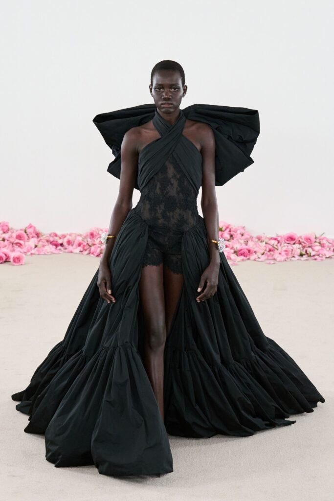 A fitted black silk sleeveless dress with a V-neckline and tiered design.