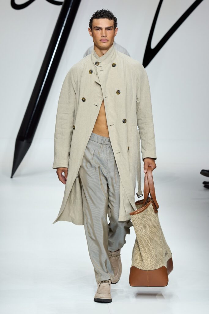 A relaxed-fit beige cotton coat with a collared neckline paired with gray straight-leg pants.
