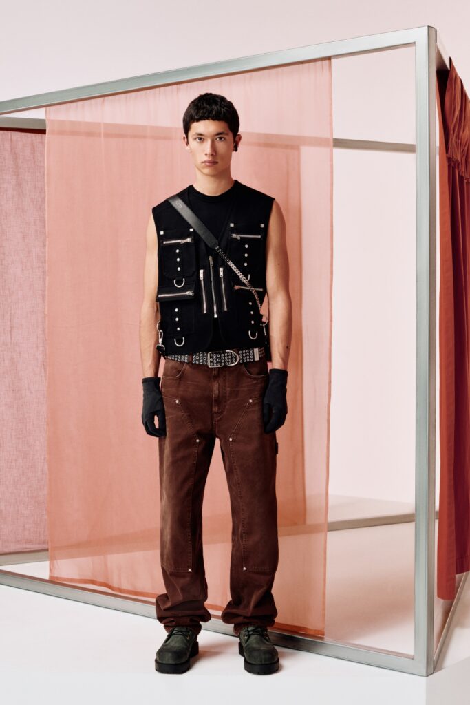 A relaxed black cotton sleeveless vest paired with high-waisted brown pants featuring buttoned and pocketed details.