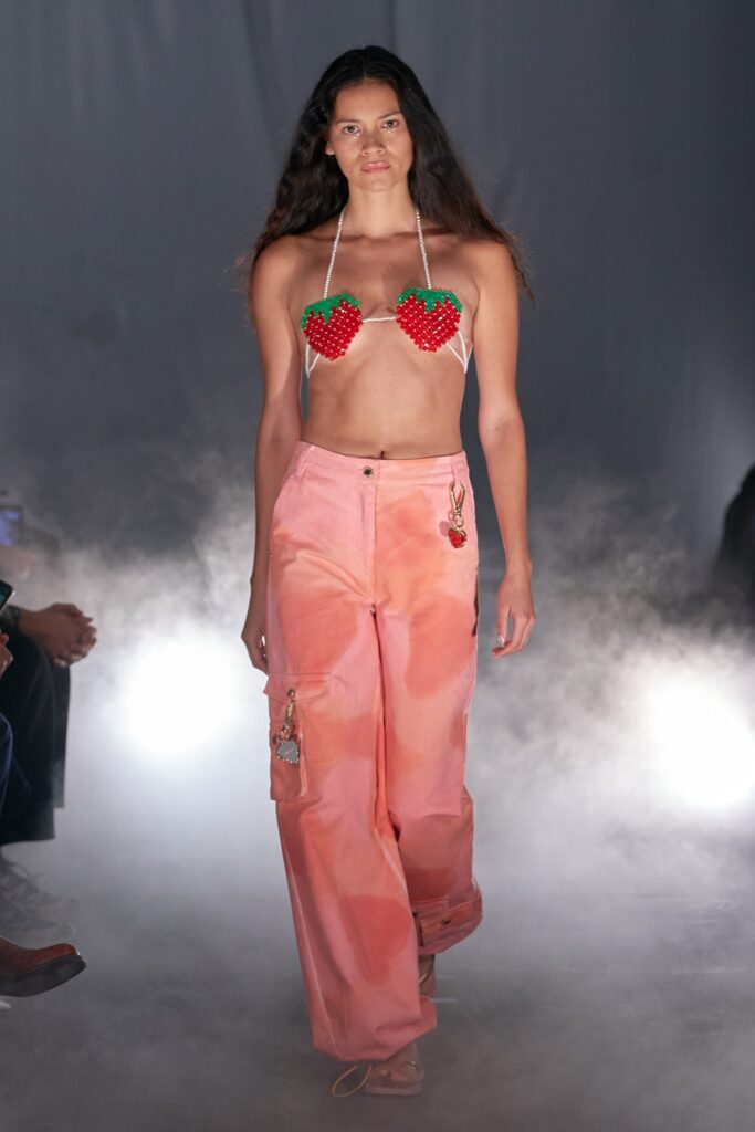 A relaxed pink sleeveless top paired with high-waisted flared pants, featuring red accents.