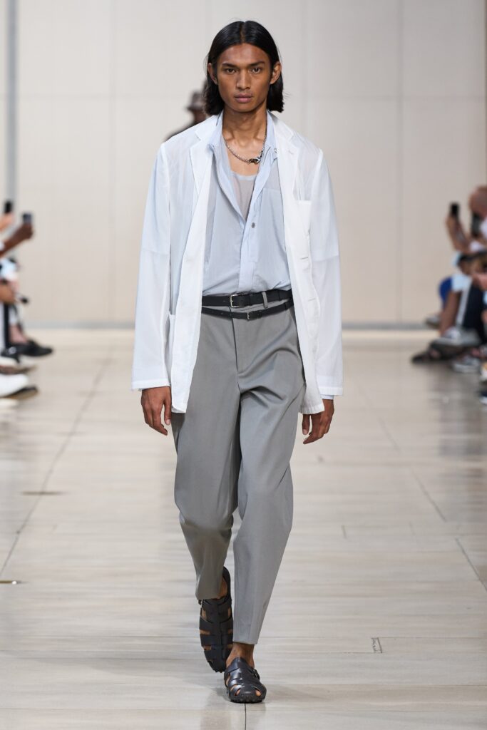 A relaxed white long-sleeve collared shirt paired with gray straight-leg pants.