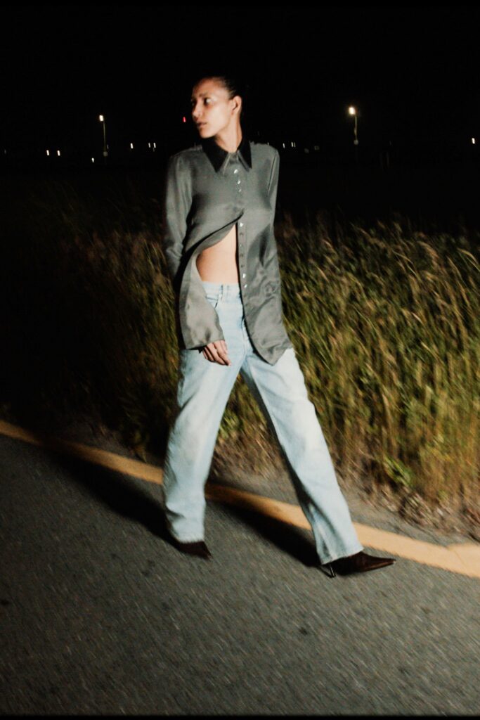 A relaxed gray long-sleeve shirt with an asymmetric design paired with wide-leg blue jeans.