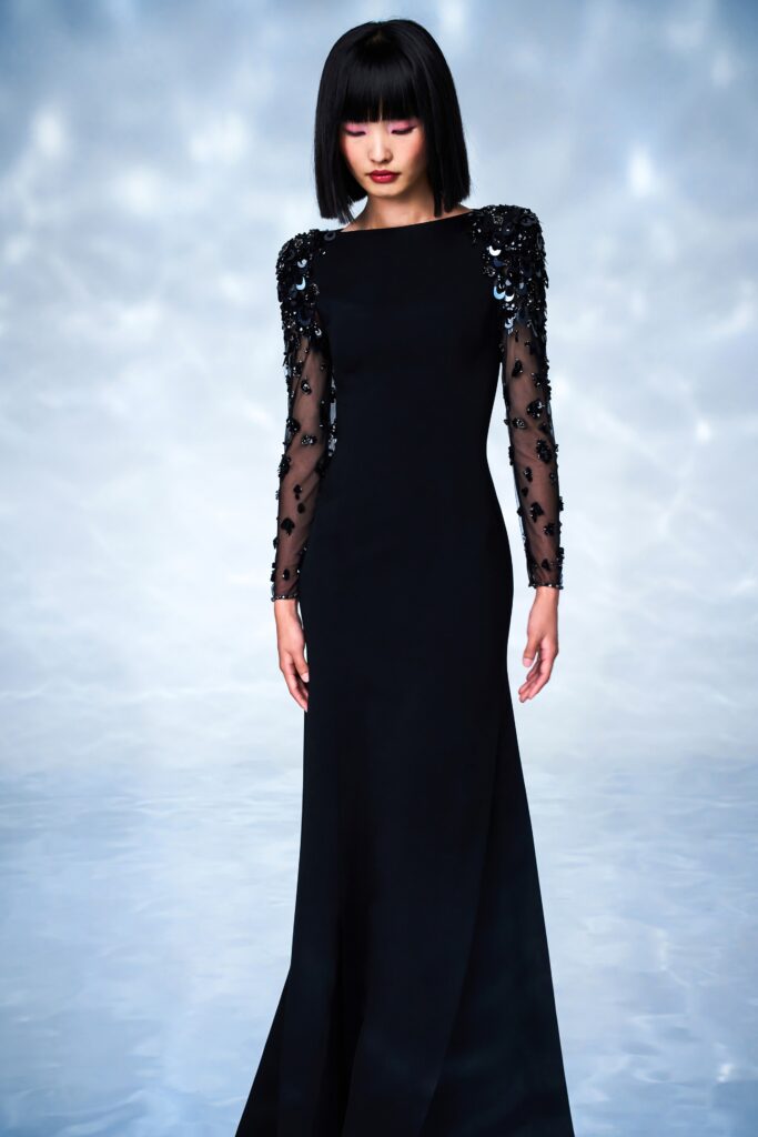 A fitted black silk gown with long sleeves and embellished detailing.