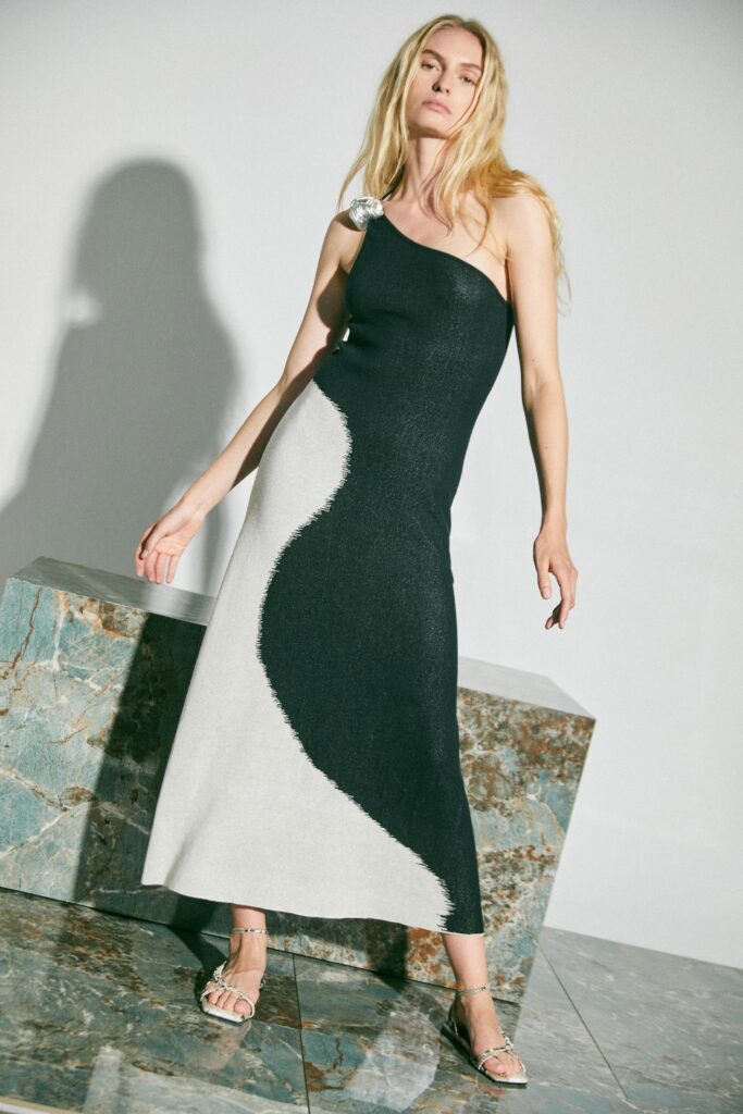 A fitted sleeveless dress featuring an asymmetric design in black and white knit fabric.