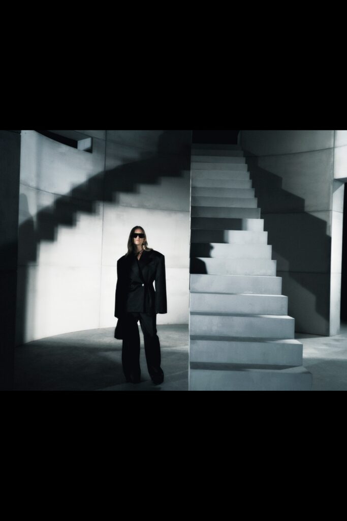 A tailored black wool suit with long sleeves and a collared design featuring straight-leg trousers.