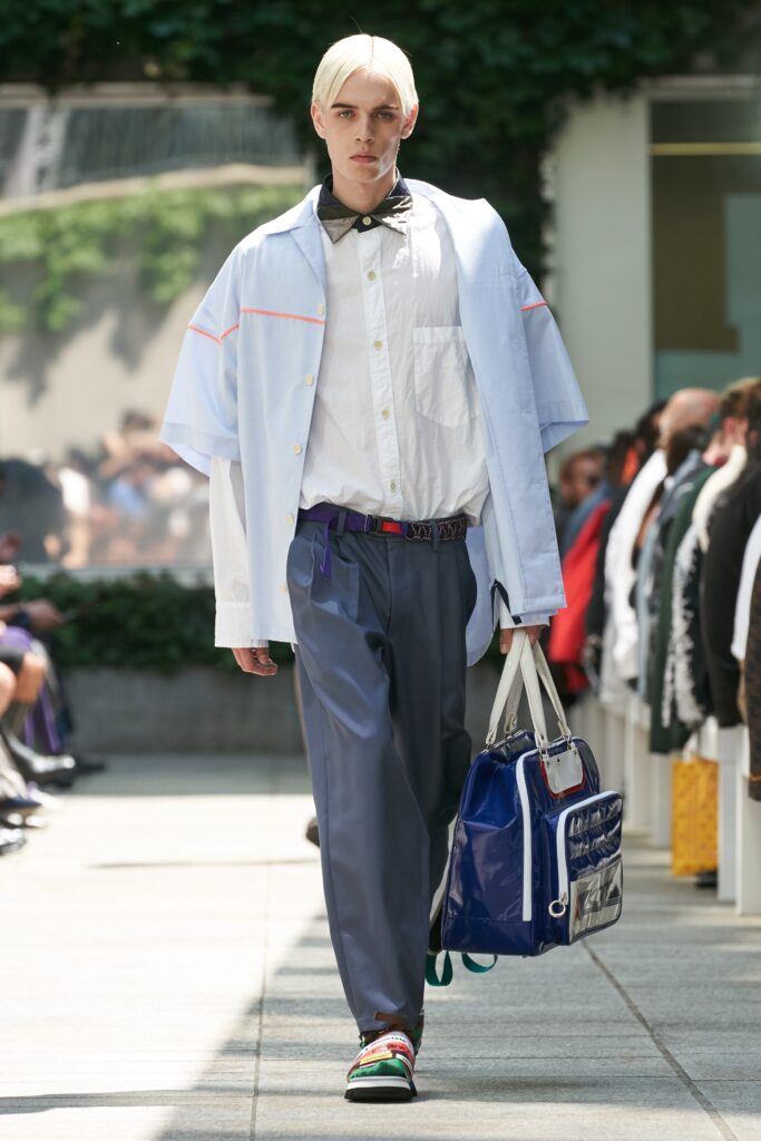 A relaxed fit white collared shirt with short sleeves paired with wide-leg blue pants.