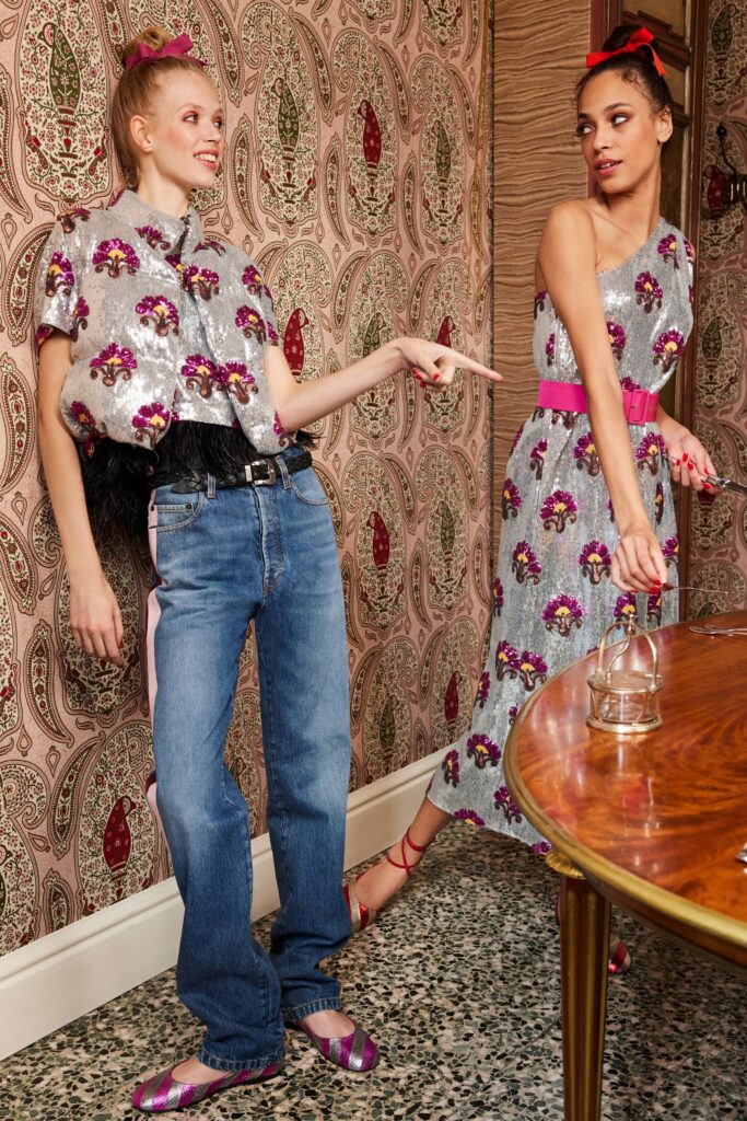 A relaxed floral gray sleeveless dress paired with blue straight-leg pants.