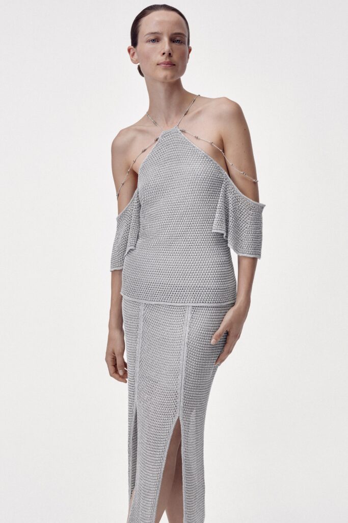 A fitted gray knit dress with an off-shoulder design and a slit detail.