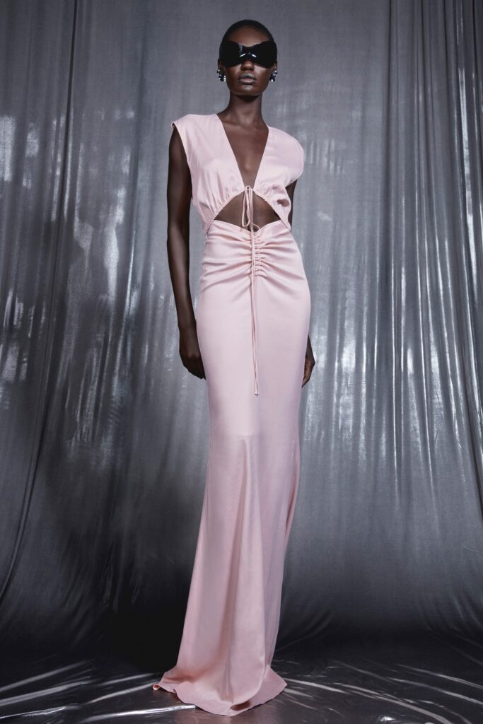 A fitted pink silk dress with a V-neckline, sleeveless design, and a stylish slit.