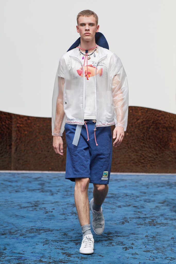 A relaxed fit white plastic jacket with short sleeves and blue cotton shorts featuring a color-blocked design.