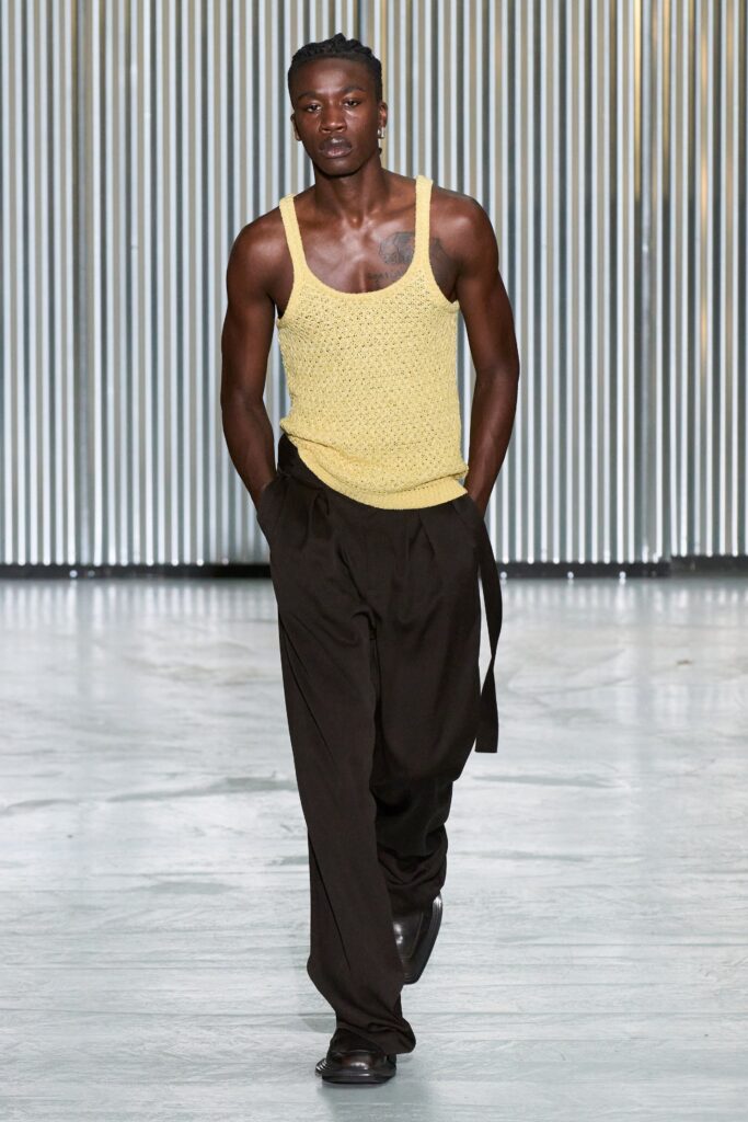 A relaxed yellow cotton sleeveless tank-top paired with high-waisted black straight-leg pants.