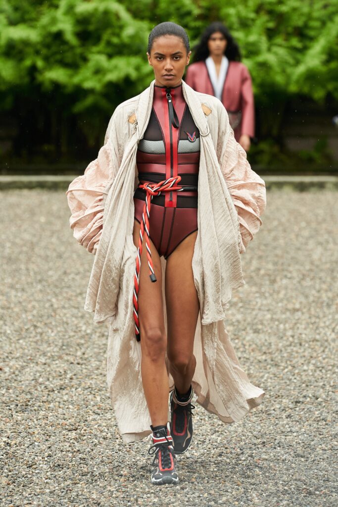 A fitted red jumpsuit layered with a beige coat featuring a collared neckline.
