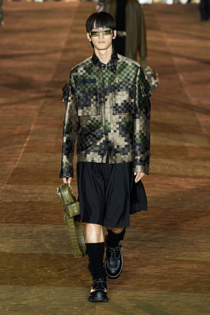 A relaxed fit green printed jacket with long sleeves and a collared design paired with a black asymmetric skirt.
