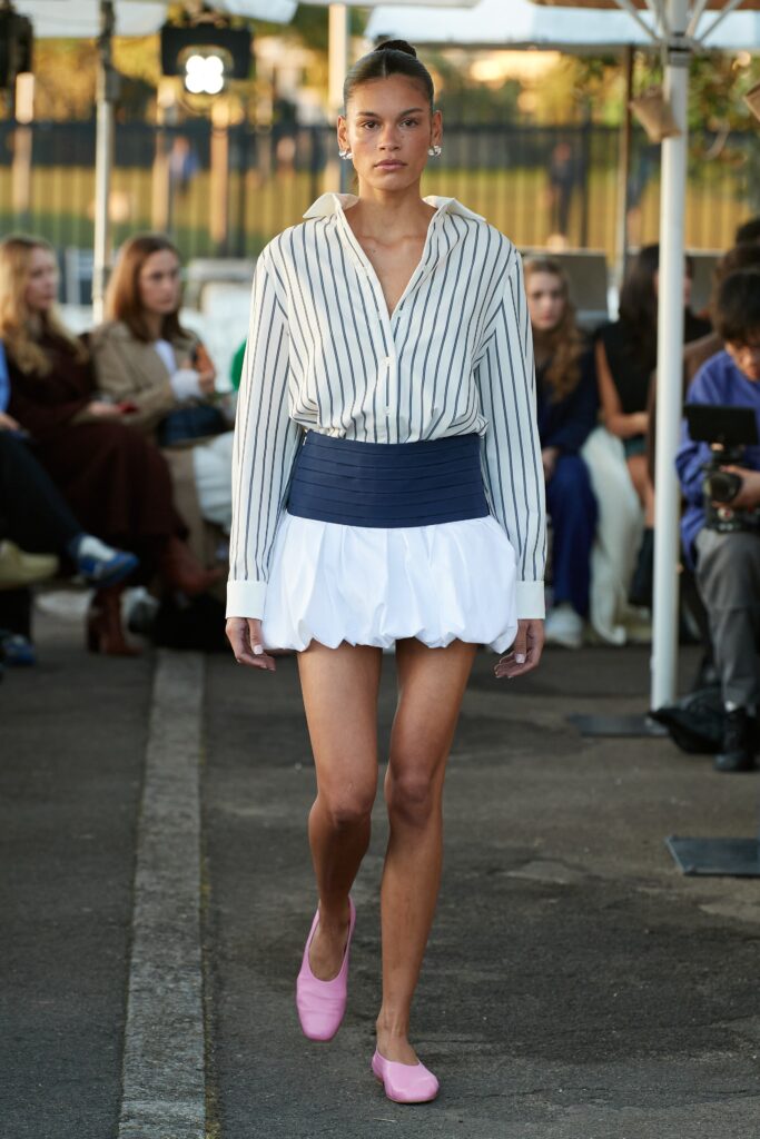 A fitted white and blue striped long-sleeve shirt paired with a pleated white skirt.