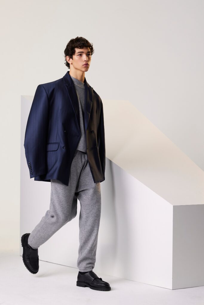 A relaxed navy blazer paired with gray pants, featuring a collared neckline and buttoned detail.