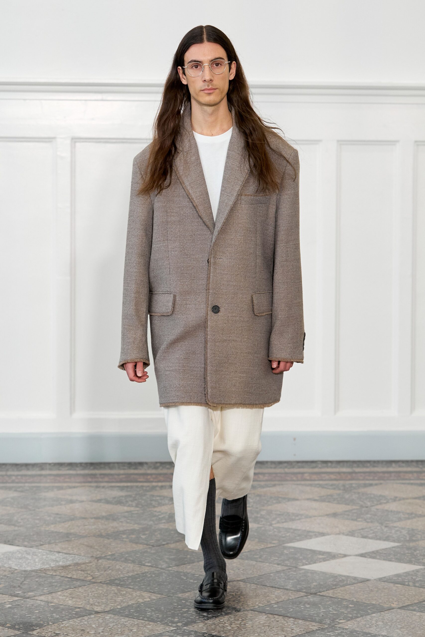 A relaxed gray wool coat paired with white cotton pants, featuring a collared design and buttoned details.