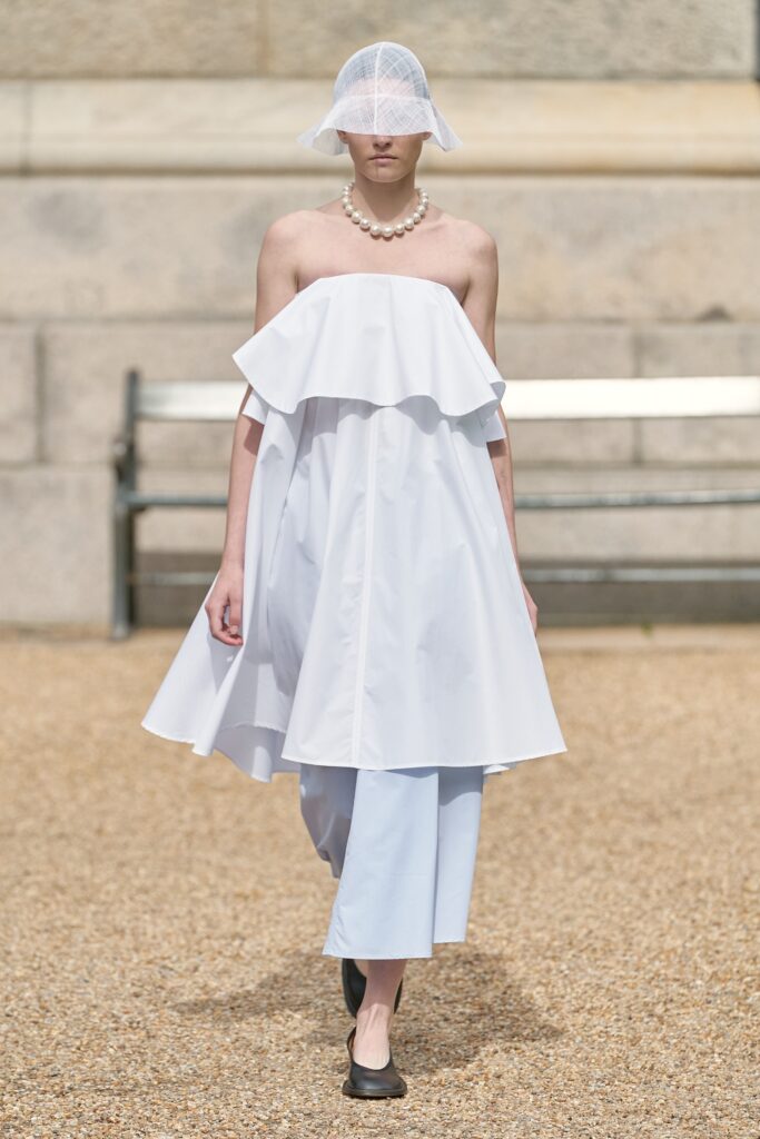A relaxed white off-shoulder layered dress paired with light blue pants.